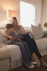 Mother with her son reading story book in living room