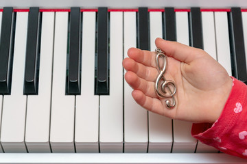 The little girl plays the piano. Hands of the musician on the piano keys while playing the instrument. Concert of Classical Music.