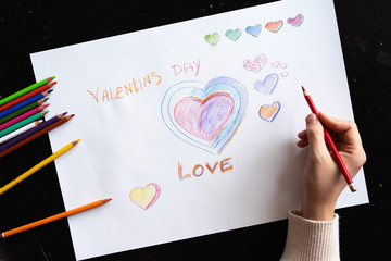 girl draws the heart and the word love pencil on paper. Valentine's day card. handmade