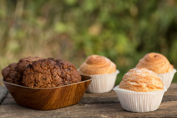 Close up fresh baked golden muffins and biscuit on rustic wooden background shot in natural light