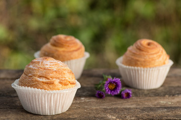 Close up fresh baked golden muffins and biscuit on rustic wooden background shot in natural light