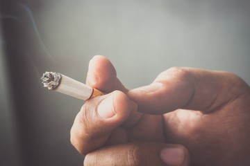man holding smoking a cigarette in hand. Cigarette smoke spread. 