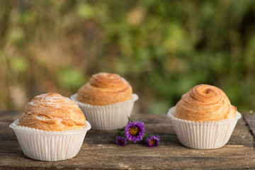 Close up fresh baked golden muffins and biscuit on rustic wooden background shot in natural light