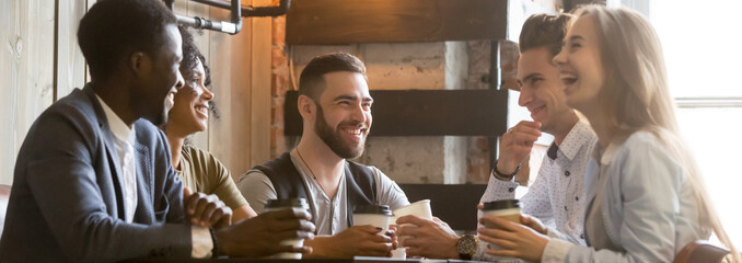 Horizontal photo happy millennial diverse friends sitting at cafe chatting having fun drink coffee enjoy time together. Multiracial friendship leisure activity concept banner for website header design
