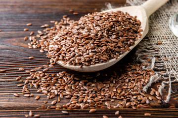 Flax seeds in wooden spoon on wooden background. 