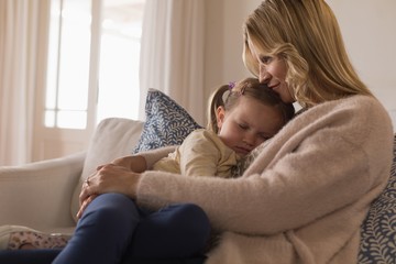 Mother embracing her sleeping daughter in arms