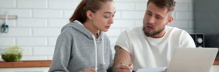 Fototapeta premium Horizontal photo millennial couple sitting at table check utilities bills read leasing loan documents. People planning family budget concept, banner for website header design with copy space for text