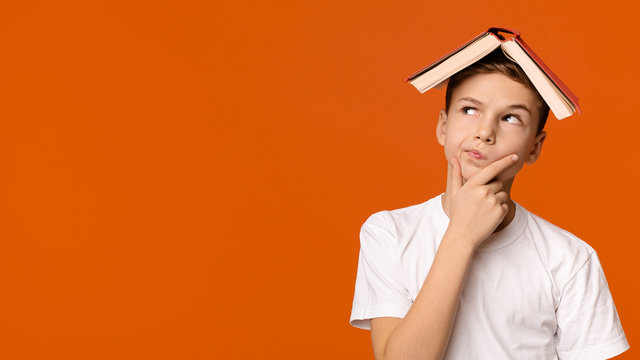 Boy with book on head thinking on orange background