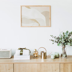 Obraz na płótnie Canvas Modern interior design concept. Minimal Nordic Scandinavian style living room with photo frame on white wall, wooden table with gift box, floral bouquet with eucalyptus, candles, radio.