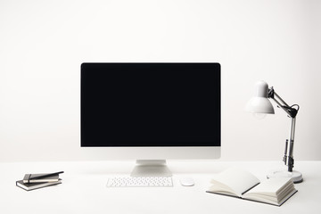 workplace with lamp, notebooks and desktop computer with copy space isolated on white