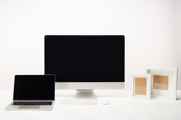 workplace with photo frames, desktop computer and laptop with copy space isolated on white