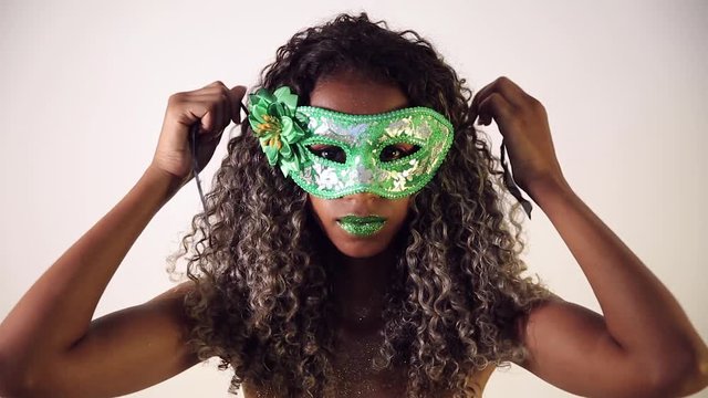 Beautiful Brazilian black female model posing in carnival mask with bright makeup and gren lipstick.
