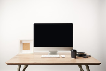 workplace with coffee to go, notebooks, photo frame and desktop computer with copy space isolated on white