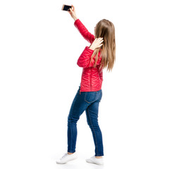 Beautiful woman in red jacket and jeans in hand smartphone selfie on white background isolation, back view