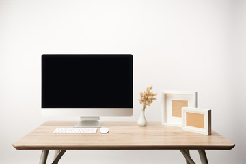 workplace with photo frames, dry flowers and desktop computer with copy space isolated on white