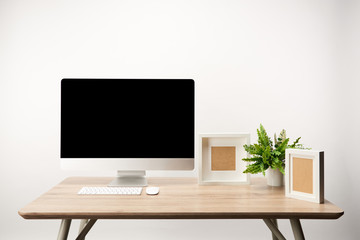 workplace with photo frames, green plant and desktop computer with copy space isolated on white
