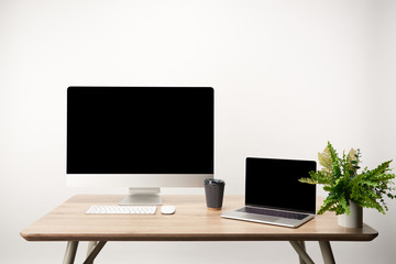 workplace with desktop computer and laptop with copy space on wooden table isolated on white