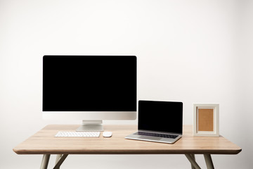 workplace with photo frame, desktop computer and laptop with copy space on wooden table isolated on white