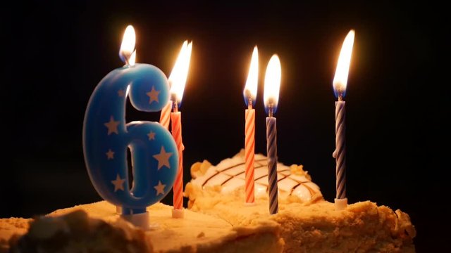 Birthday cake with burning candles on it over black background. Six years old party 