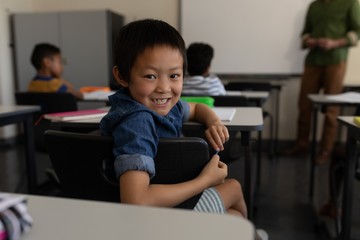 Happy schoolboy looking back in classroom