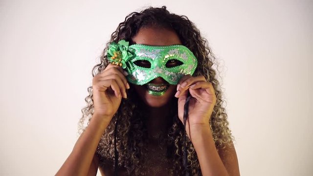 Beautiful Brazilian black female model posing in carnival mask with bright makeup and gren lipstick.