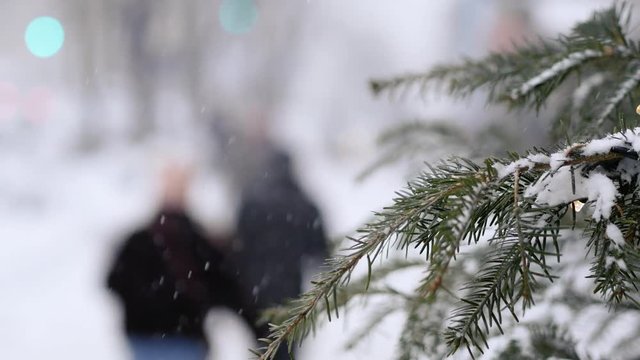 A busy city during a snowfall. Spruce with garland in the foreground