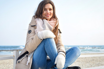 Young beautiful woman sitting on the beach on a bench and smiling.