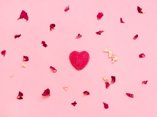 Valentine's day background Top view Pattern with heart-shaped candy and many colorful rose petals on a light pink backdrop