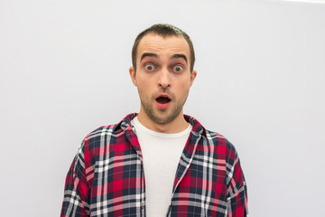 Portrait, guy  shocked in casual clothes, opening his mouth in surprise, looking at camera, white background, front view