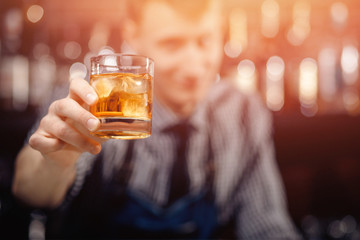 Barman serves client, gives glass of whiskey with ice double portion