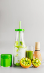 Healthy vegan layered matcha latte drink in bottle with drinking straw standing on table at light gray background. Matcha espresso. Clean eating, detox beverage, dairy food concept. Summer drinks