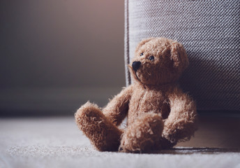 Teddy bear is laying down on carpet in retro filter, Lonely teddy bear laying down alone in living...