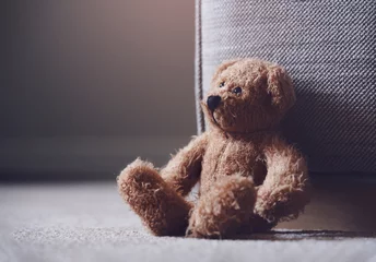 Fotobehang Teddy bear is laying down on carpet in retro filter, Lonely teddy bear laying down alone in living room at night ,lonely concept, international missing children's day. © Anchalee