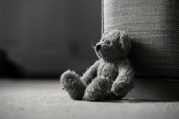 Teddy bear is sitting down on carpet in retro filter, Lonely teddy bear sitting alone in living...
