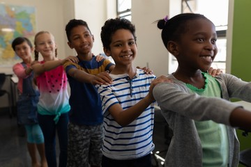 Side view of school kids standing in row with their hands on