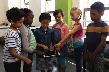 Group of school kids studying together on digital tablet in