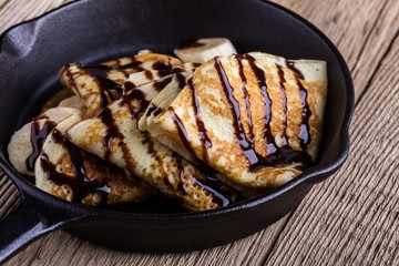 Crepes with bananas and chocolate topping for breakfast