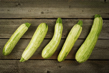 Fresh organic zucchini or green courgette on rustic background, farm fresh produce, summer squash, top view or flat lay.