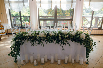 Wedding table decoration with the white flowers and greenery for the fiance and fiancee at the restaurant