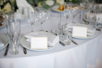 White dishes on the wedding table with empty cards. Wedding decoration in the rastaurant