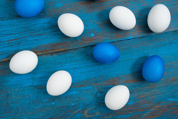 Creative egg layout painted blue and white on a blue wooden background