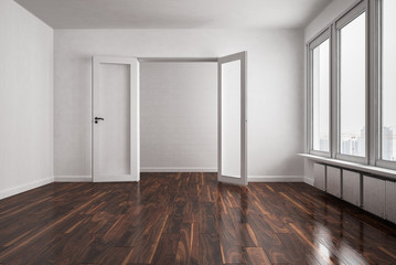 Leere Wohnung mit großer Fensterfläche und dunklem Holzfußboden
