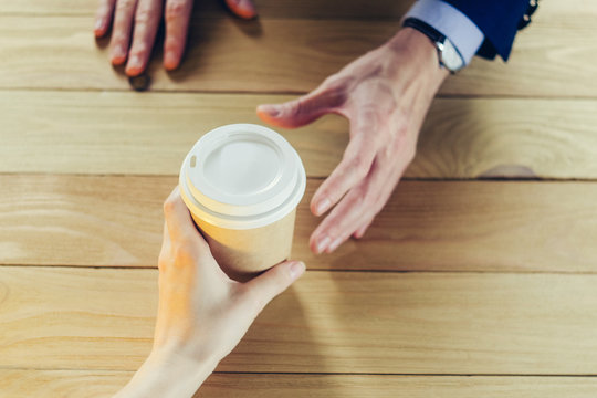 Barista serves coffee to a man. Hand Paper cup Plastic cap Wooden table Break Blazer. Coffee Break Concept
