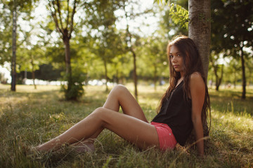 Naklejka na ściany i meble Beautiful brunette girl posing for photo at the park in pin shorts