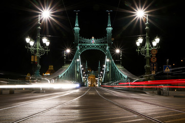 A picture of the Liberty bridge in Budapest, Hungary at night with the light traces from the cars. 