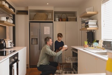 Father and son arranging dirty dishes in dishwasher