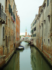 Fototapeta na wymiar View to one of the venetian bridge with rio del greci and bell tower of basilica di San Giorgio Maggiore on the background, Venice, Italy