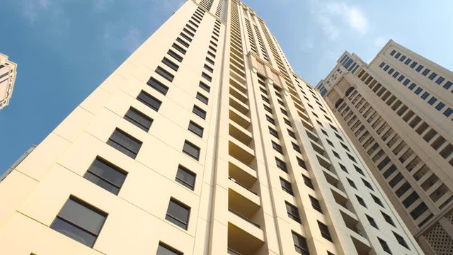 Dubai, UAE. Skyscrapers of dubai. High-rise apartment building in Dubai against the blue sky. Smooth camera movement. Radically low angle video on high-rise building