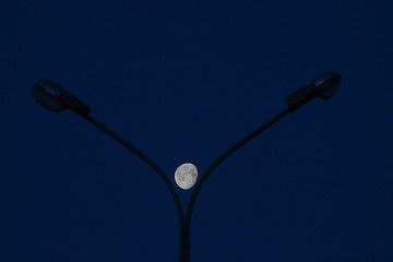 lunar urban landscape. the moon lies between two lanterns that illuminate the street. the night on the street