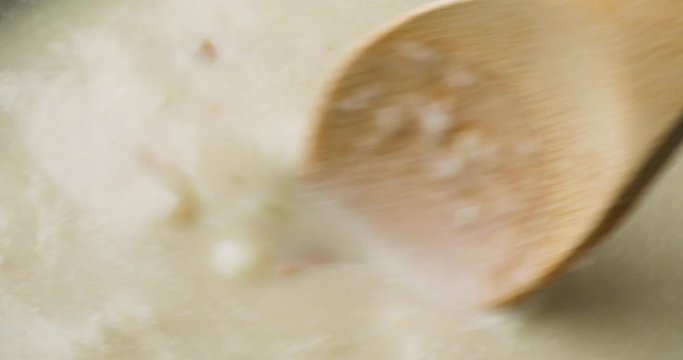 Close video of slowly stirring canned clam chowder with a wood spoon while cooking.